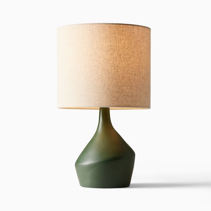 a green table lamp with a beige shade