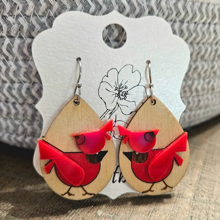 wooden earrings with red cardinals on them and a white flower in the back ground