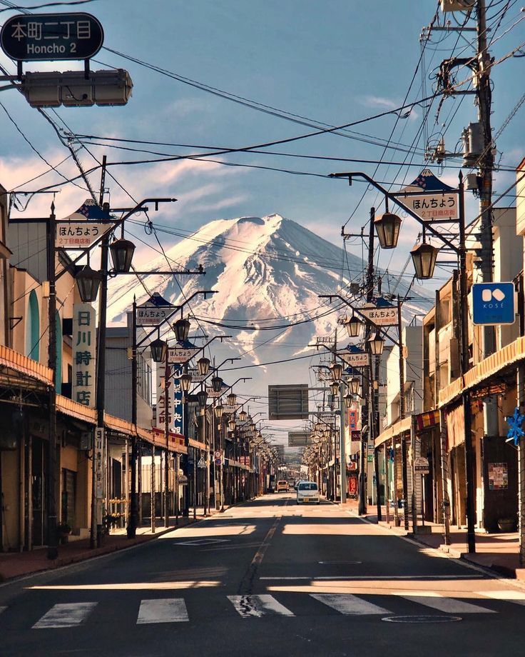 an empty city street with mountains in the backgrouds and telephone wires above it