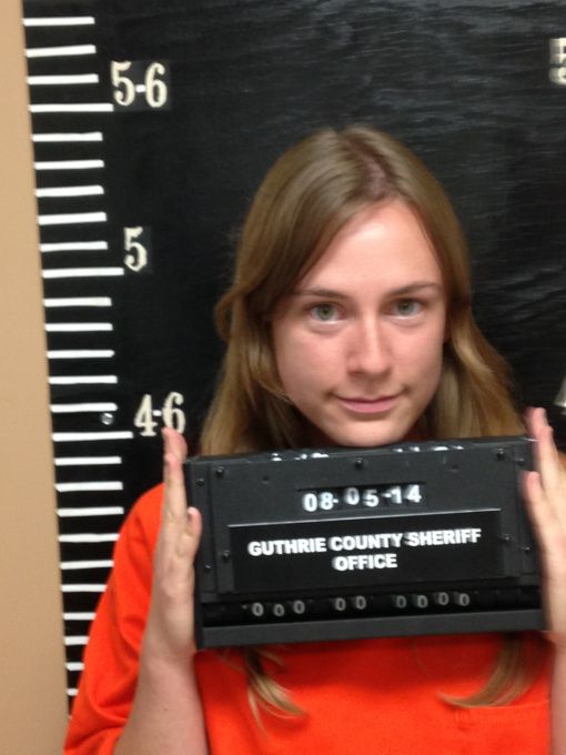 a woman in an orange shirt holding up a sign