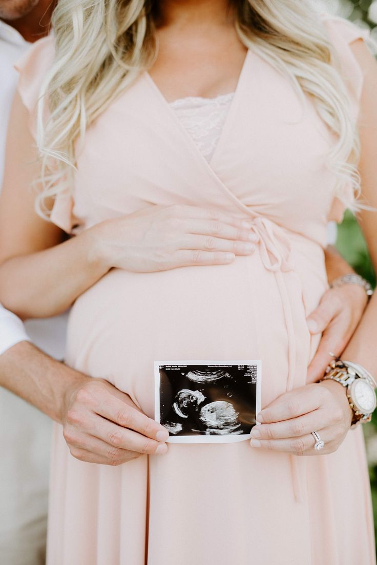 a pregnant woman is holding her belly in front of the camera, while she holds it up