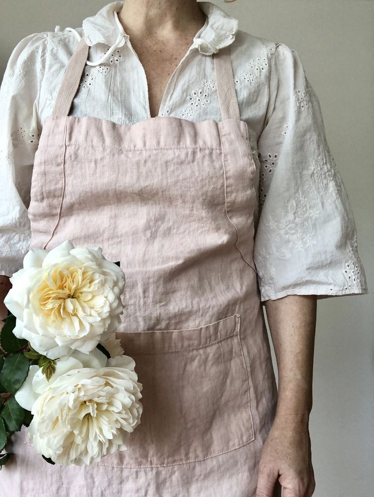 a woman wearing an apron holding flowers in her hands