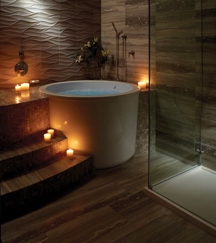 a bathroom with candles lit on the floor next to a bathtub and shower stall