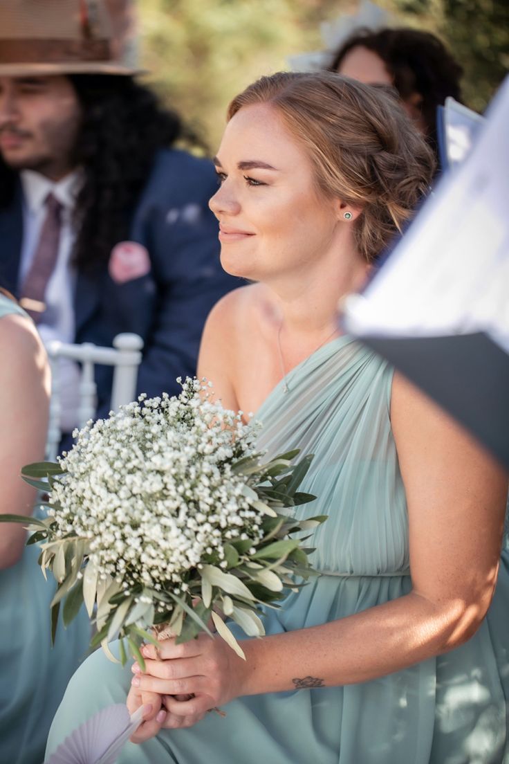 a woman holding a bouquet of flowers in her hand while standing next to other people