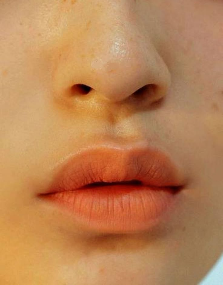 a woman's face with freckles on her nose and lip piercings