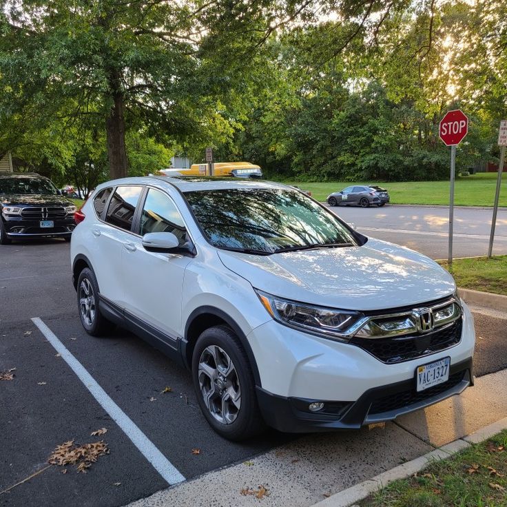 a white honda cr - v parked in a parking lot next to a stop sign