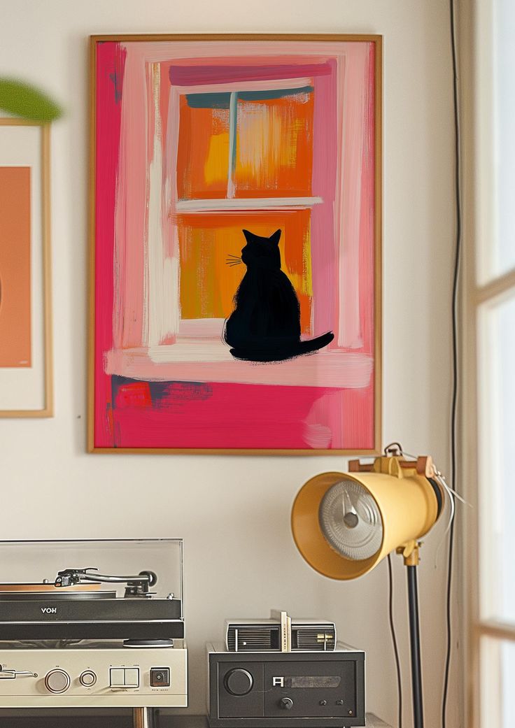 a cat sitting on top of a table next to a record player and a lamp