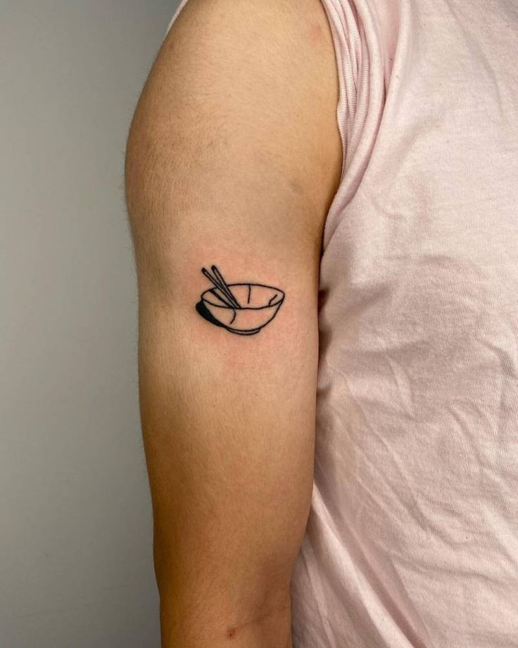 a man with a black and white tattoo on his arm holding a bowl of noodles