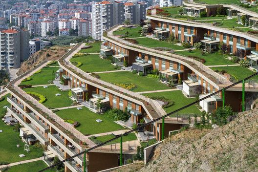 an aerial view of a city with many buildings and green roofing on the hillside