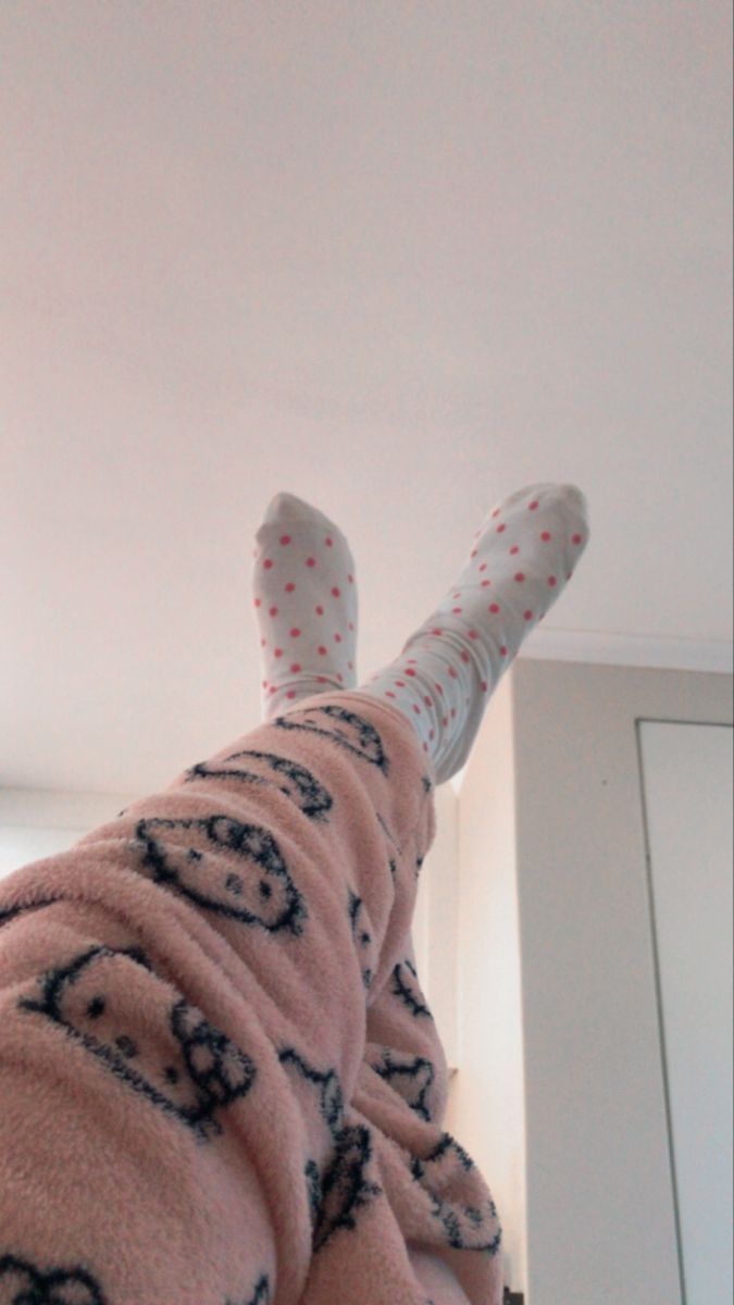 a person in pink pajamas laying on top of a bed with white walls and ceiling