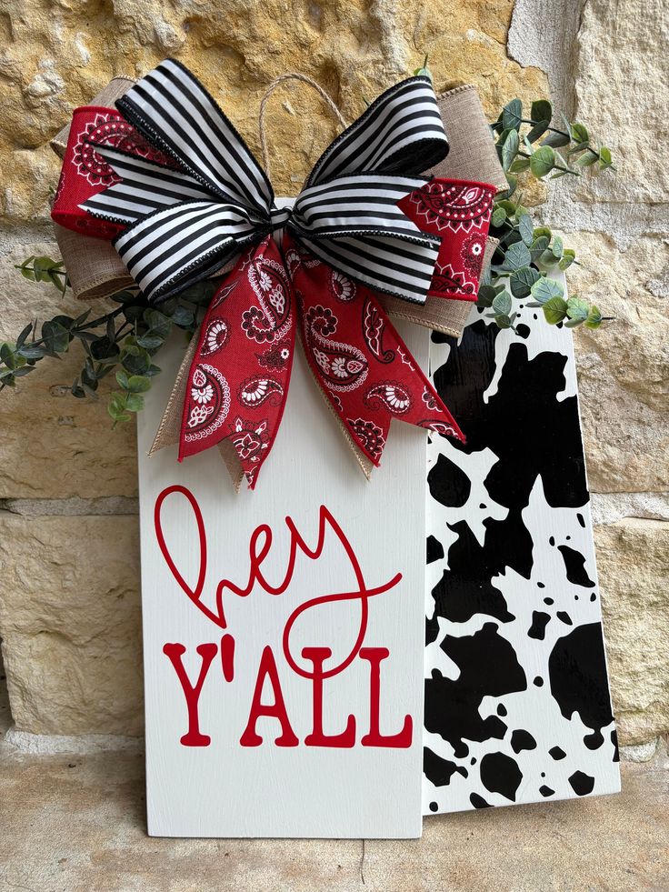 a sign with a bow on it that says hey y'all in front of a stone wall