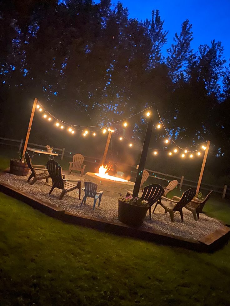 an outdoor fire pit surrounded by chairs and string lights