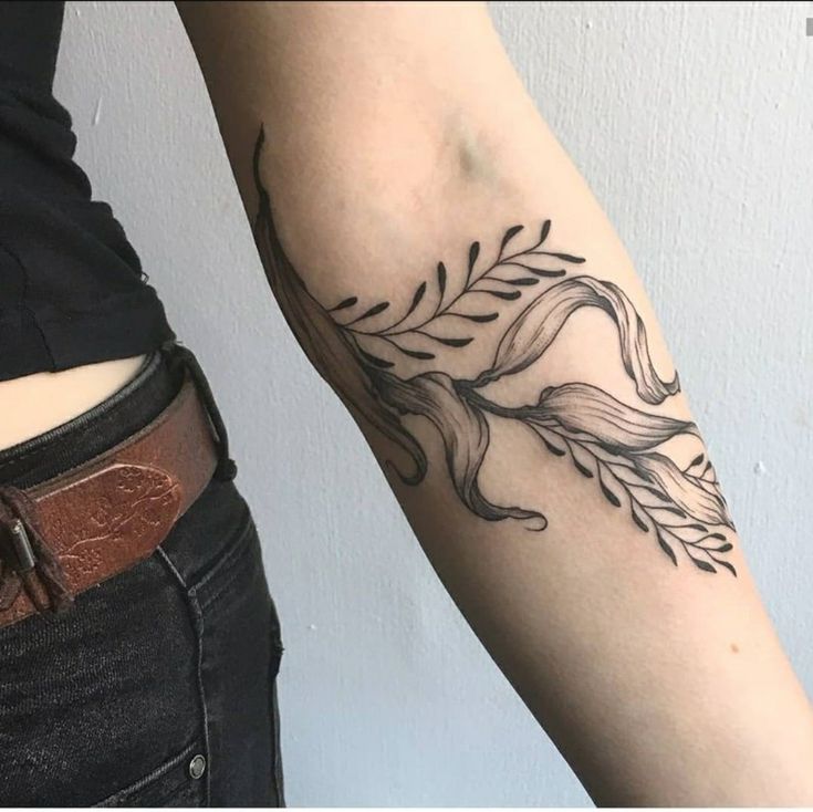 a woman's arm with a black and white tattoo design on the left forearm