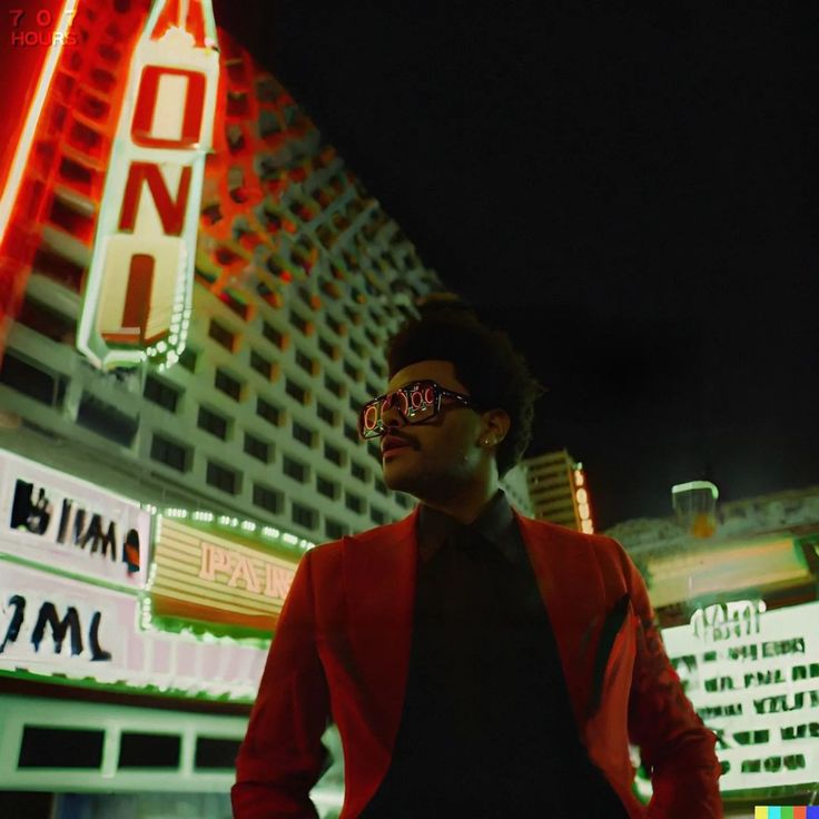 a man standing in front of a building with neon signs on it's sides