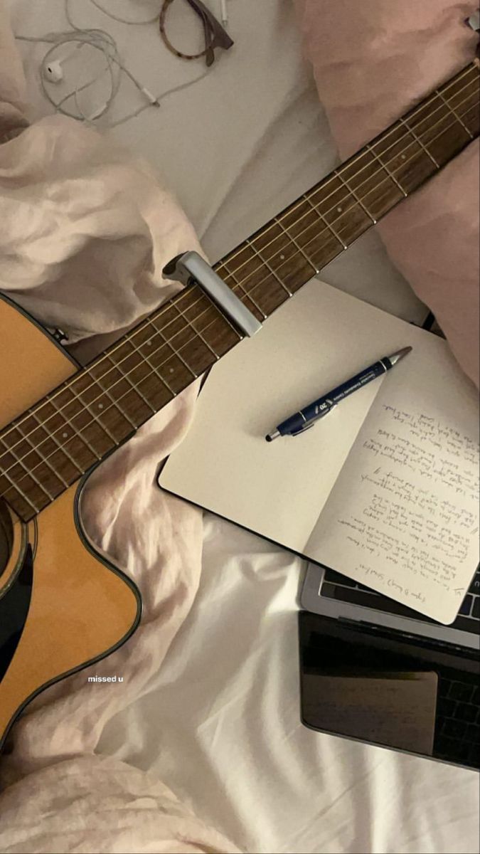 an open notepad sitting on top of a guitar