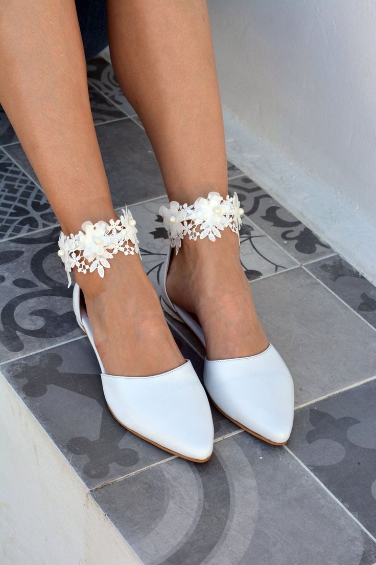 a woman's legs wearing white shoes with flowers on the ankle and heel straps