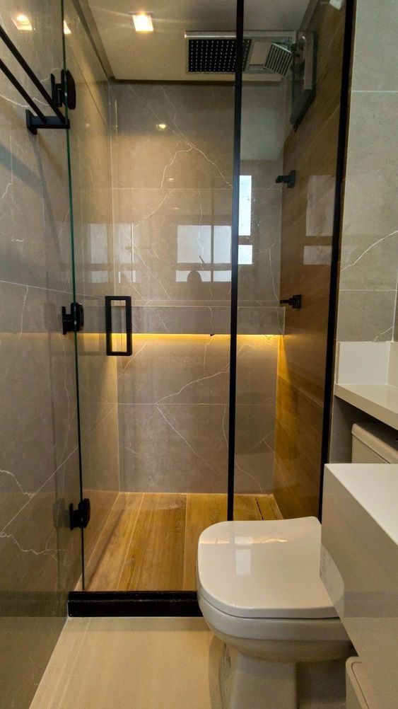 a bathroom with a glass shower door and wooden flooring, along with a white toilet