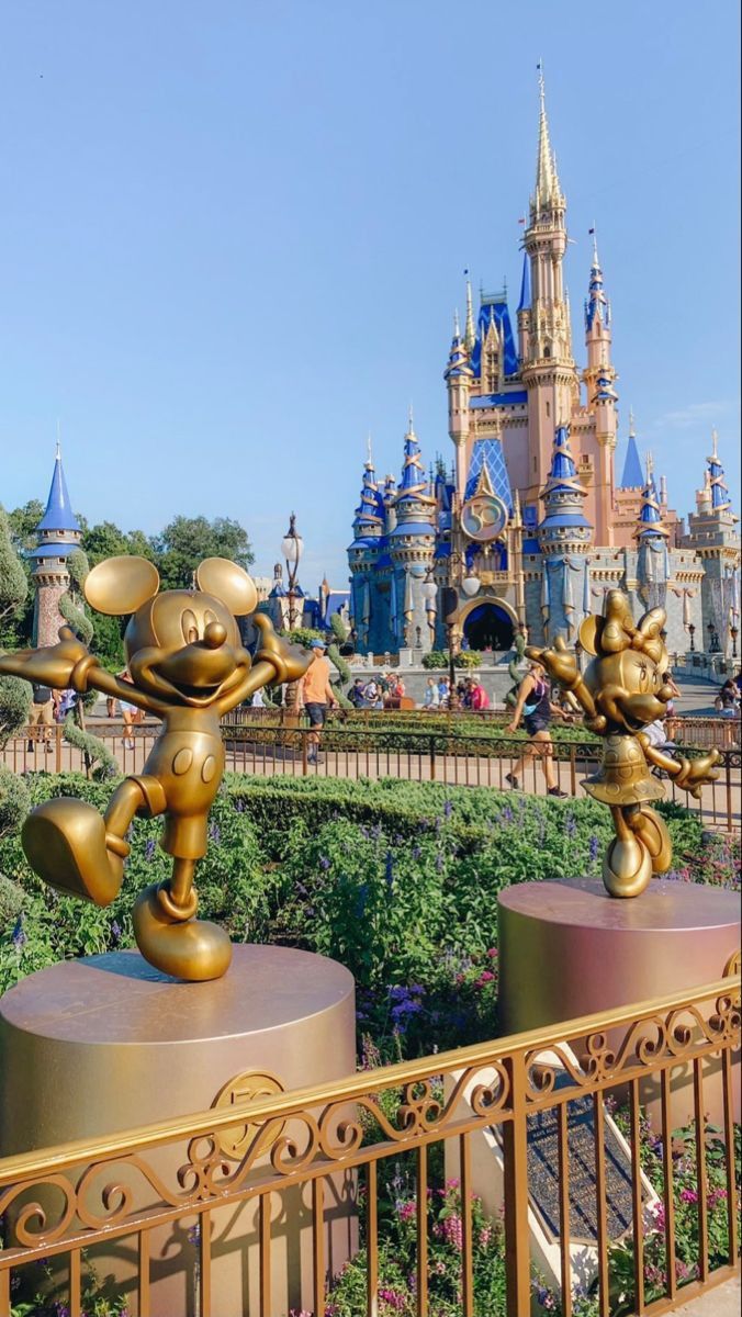 the golden mickey mouse statue is in front of disney's castle