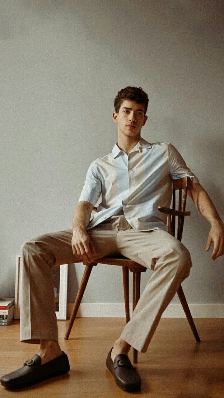 a man sitting in a chair with his legs crossed and wearing slippers on the floor