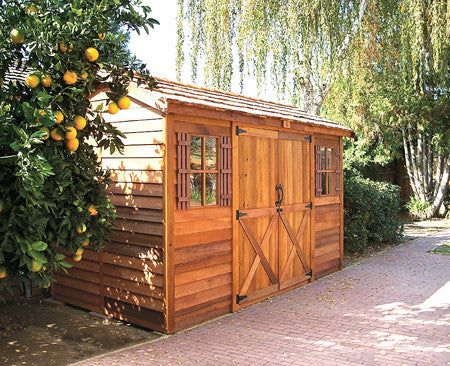 an orange tree next to a wooden shed