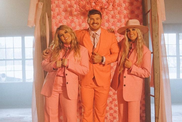 two women and a man in pink suits standing next to each other