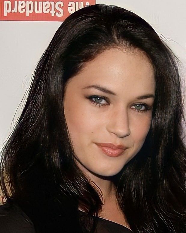 a woman with long dark hair and blue eyes posing for the camera at an event