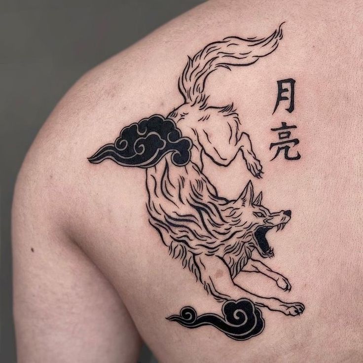 the back of a man's shoulder with a wolf and clouds tattoo on it