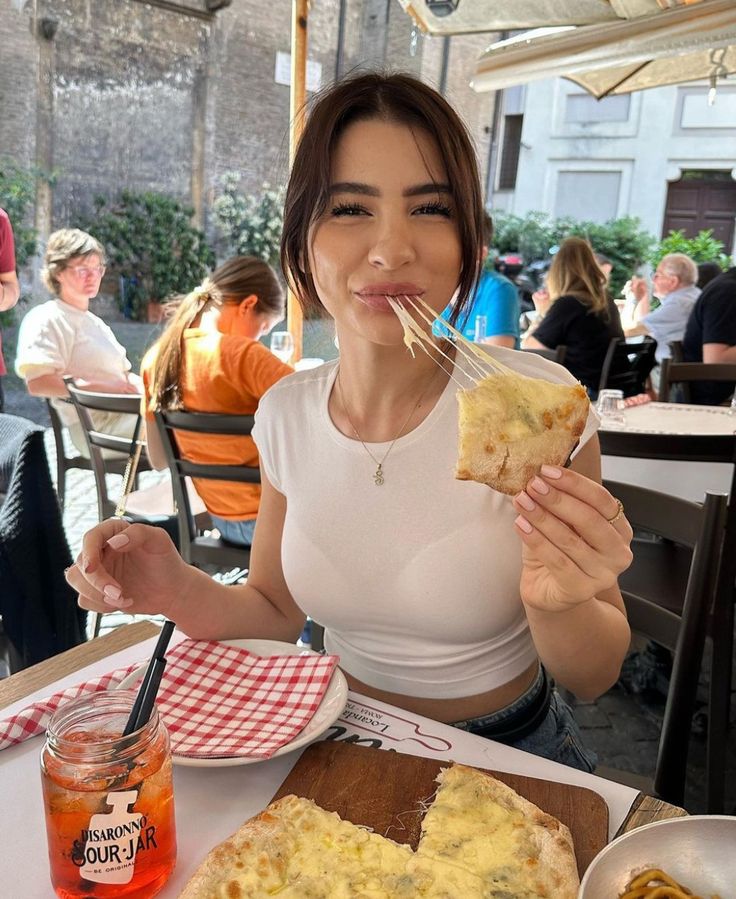 a woman sitting at a table with food in front of her and drinking from a straw