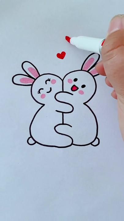 someone is drawing a bunny and rabbit hugging each other on the paper with a marker