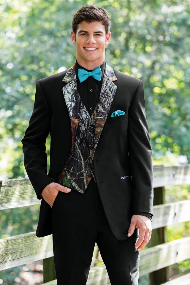 a young man in a suit and bow tie posing for a photo on a bridge