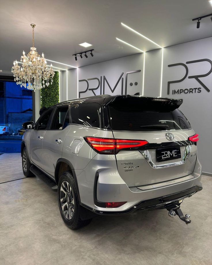 the rear end of a silver suv parked in a showroom with chandelier