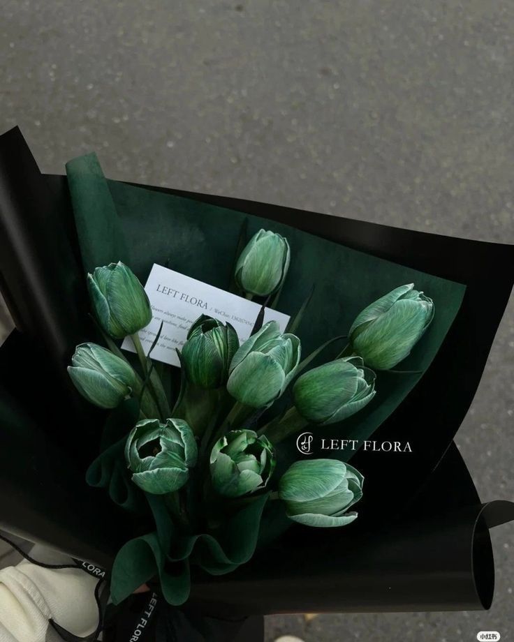 a bouquet of tulips is wrapped in black paper with a white tag on it