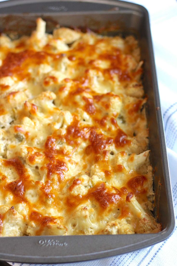 a square casserole dish with cheese and meat toppings in it on a white towel