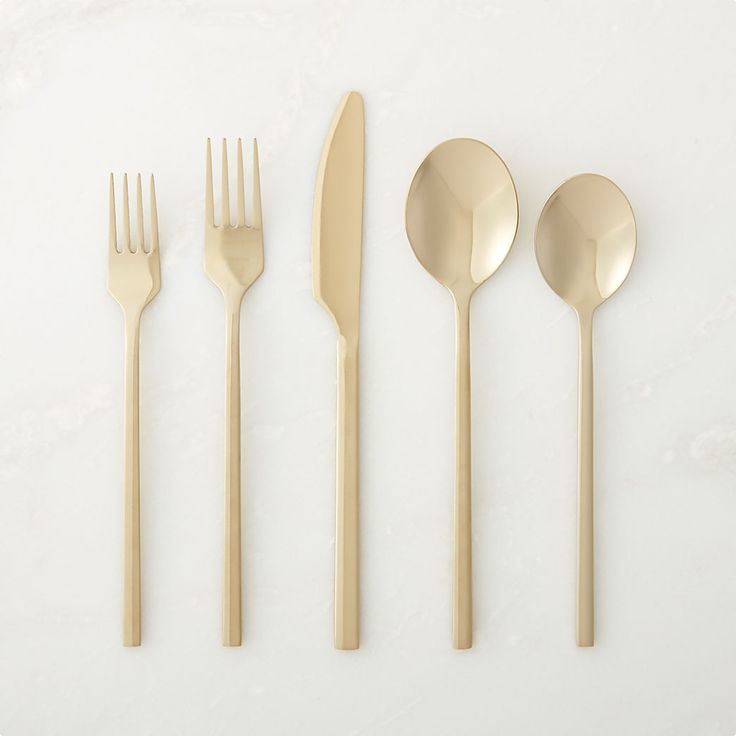 gold flatware is laid out on a white surface