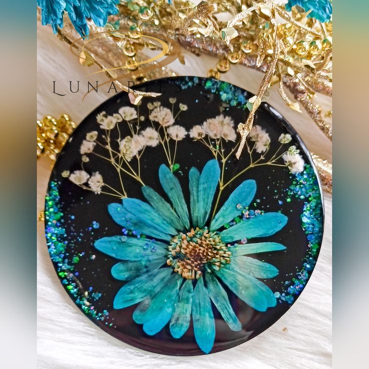 a black plate with blue flowers painted on the side and gold trimming around it