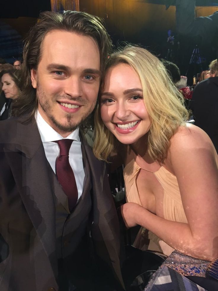 a man in a suit and tie next to a blonde haired woman at an event