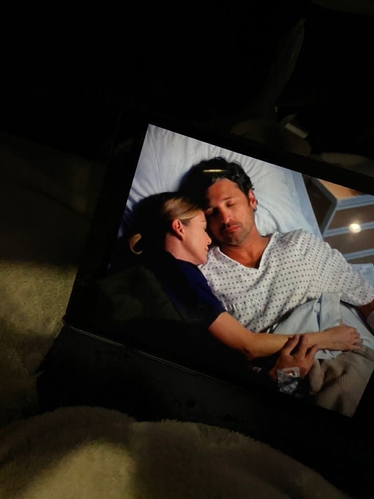 a man laying in bed with his arm around a woman's head while she sleeps