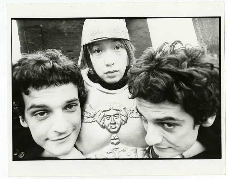 two men and a woman are posing for a black and white photo with one man wearing a helmet