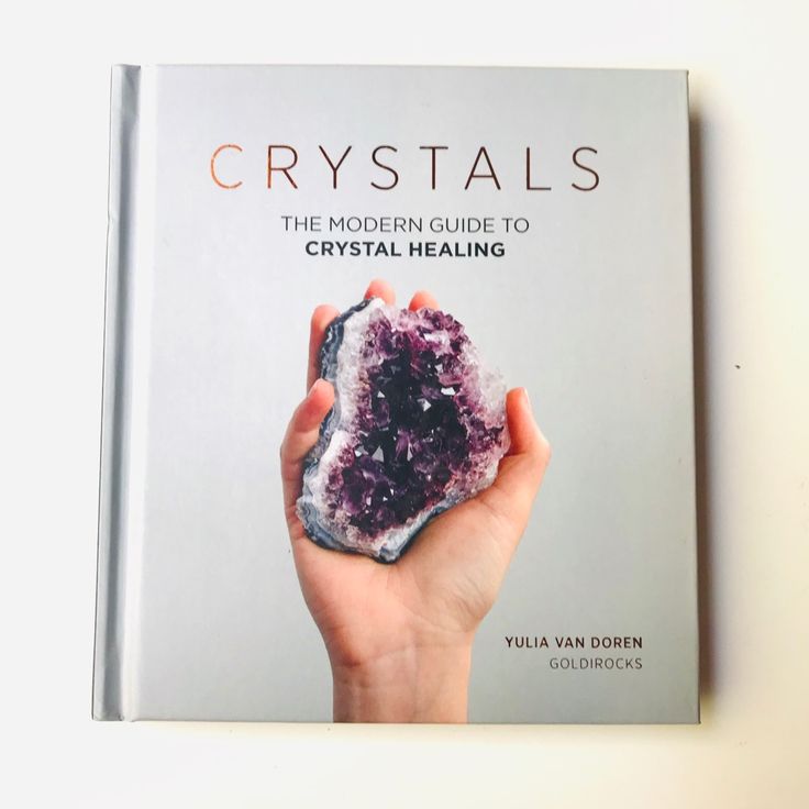 a hand holding a crystal on top of a book cover that reads crystals the modern guide to crystal healing