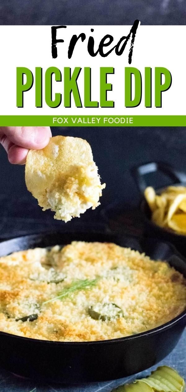 a hand holding up a piece of fried pickle dip over a skillet filled with food