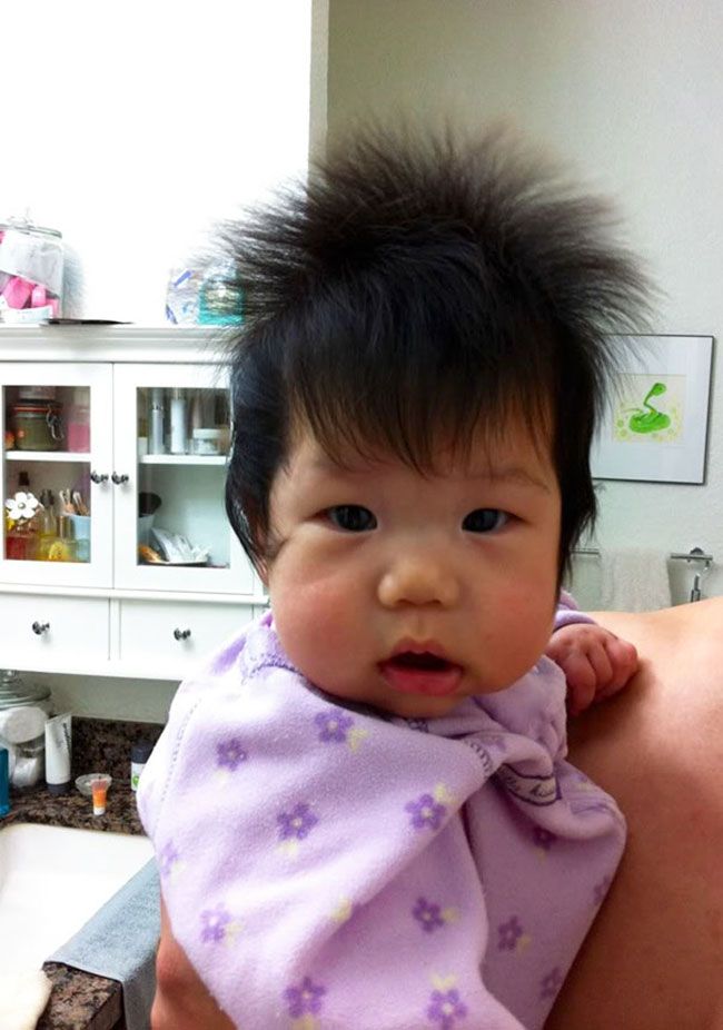 a woman holding a baby in her arms with hair on top of it's head