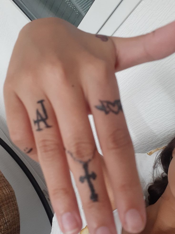 a person with tattoos on their fingers pointing at the camera