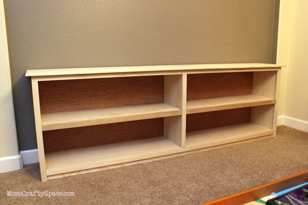 an empty book shelf in the corner of a room with carpeted floor and walls