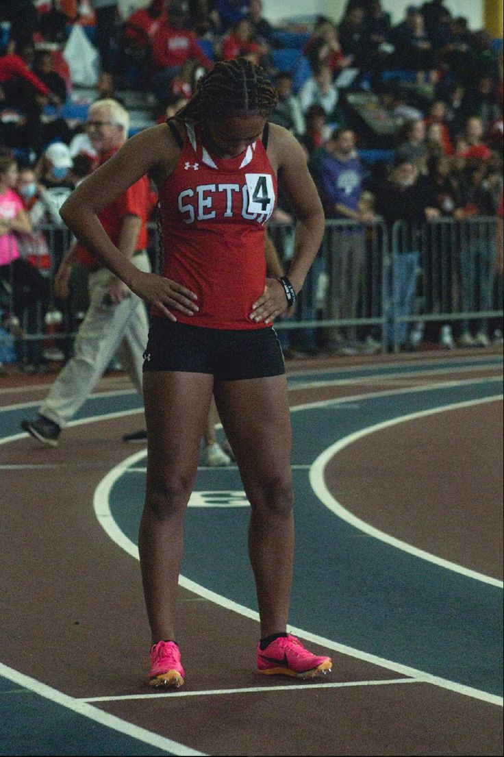 a woman standing on top of a track next to a crowd