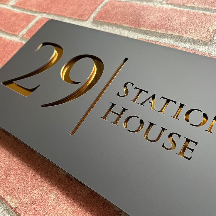 a metal sign that says station house on the side of a brick wall with gold lettering