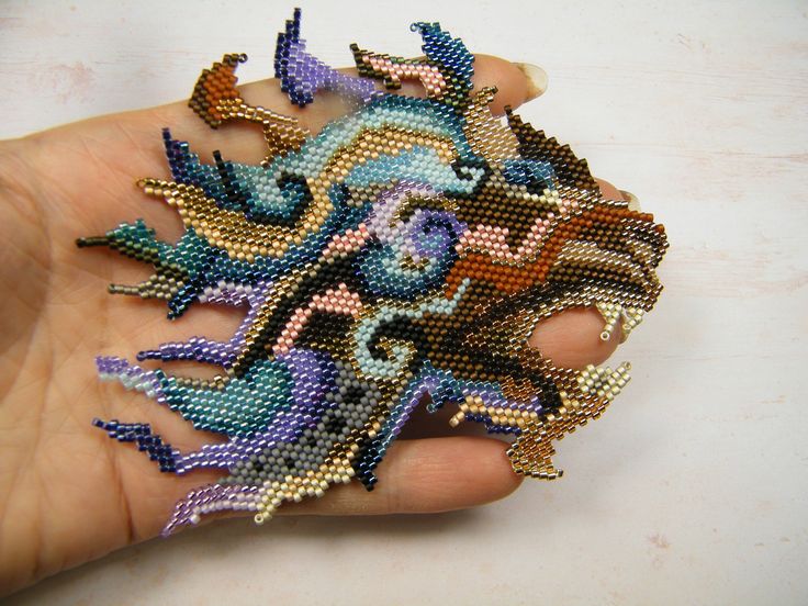 a hand holding a piece of beaded art