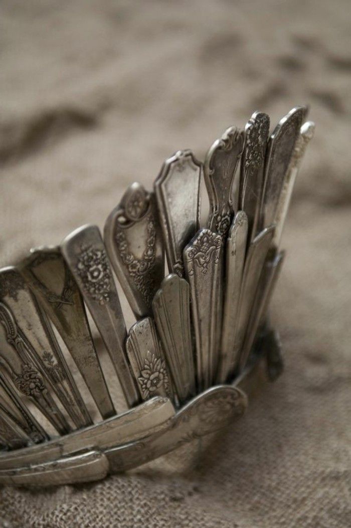 a bunch of silver spoons are in a metal holder on a tablecloth surface