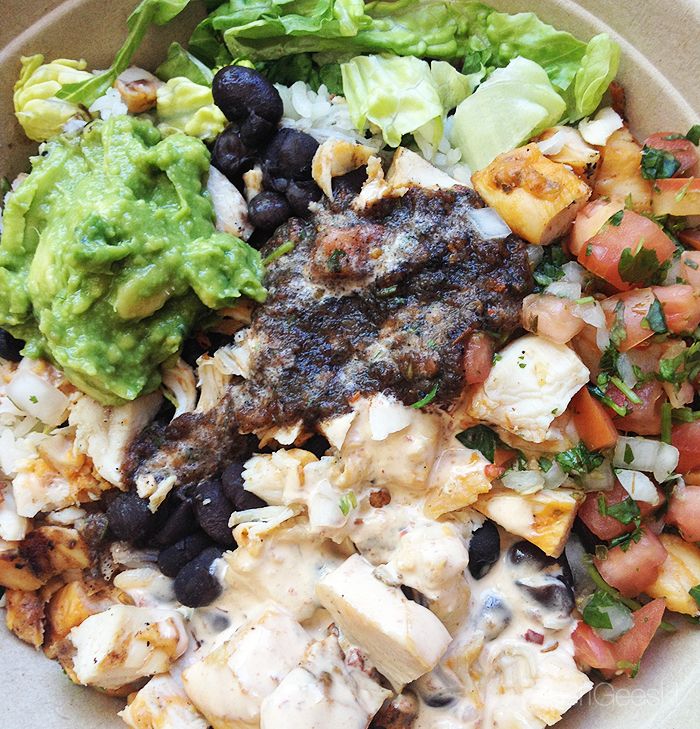 a salad with chicken, lettuce, tomatoes and black beans in a bowl