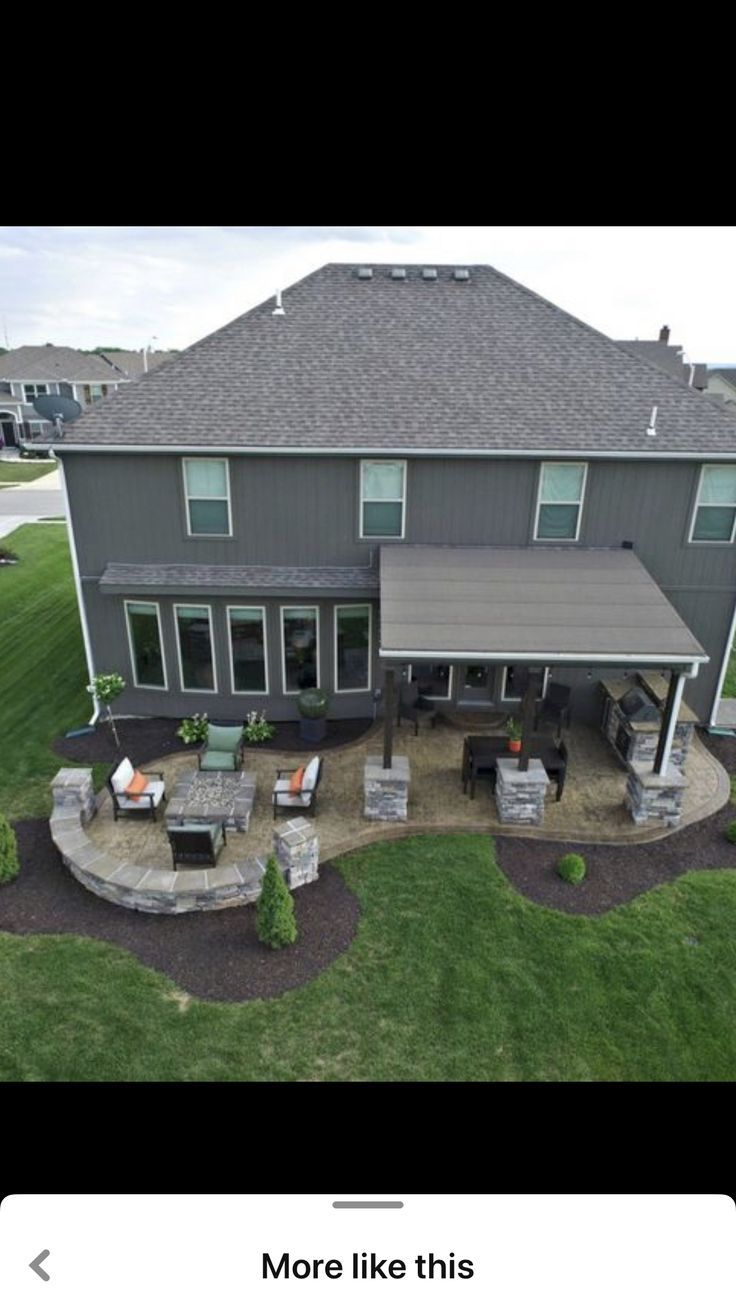 an aerial view of a large house with patio and covered in stone seating on the lawn