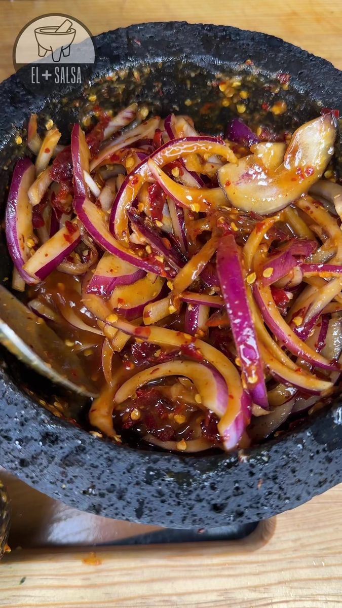 a pan filled with onions and sauce on top of a wooden table